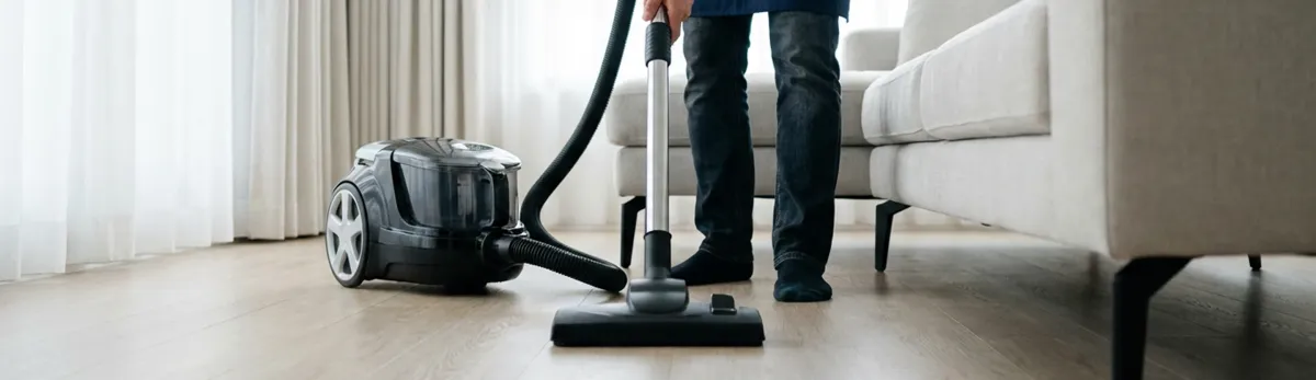 Professional house cleaner vacuuming a living room floor with a canister vacuum cleaner, Stamford, CT.